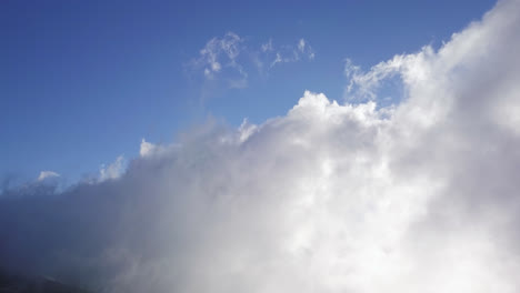 Wide-view-of-clouds-moving-over-the-slopes-of-a-mountain-on-a-sunny-day