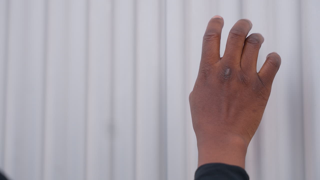 black hand covered in fine sand, fingertips brushing corrugated metal, grainy residue on skin, intimate closeup study of texture and touch frames evoke beachcomber cleaning finds, artist applying