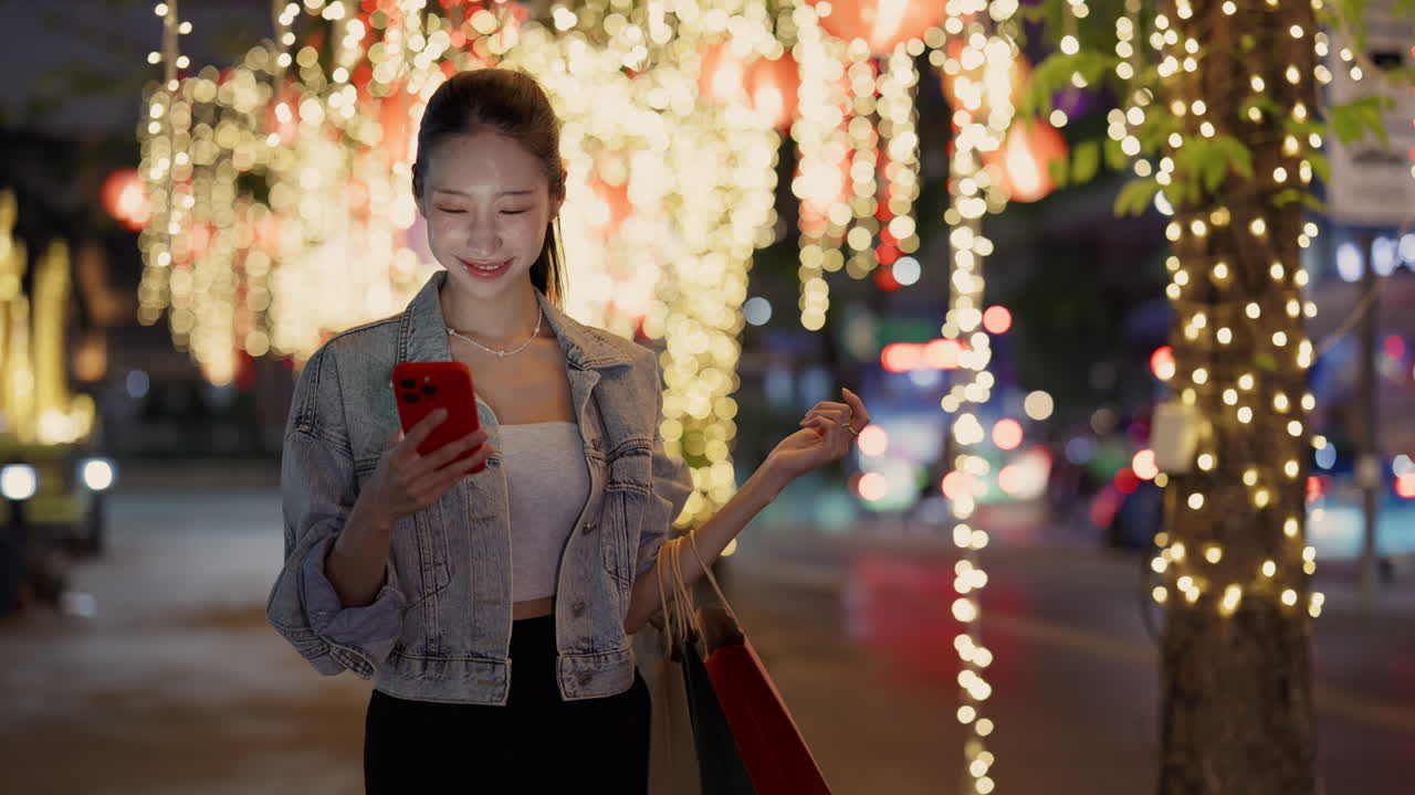 Woman with shopping bags using cellphone at night