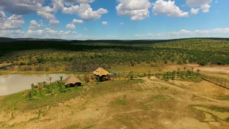 Vista-De-Imágenes-Aéreas-Del-Arbusto-Africano-Con-2-Estructuras-Con-Techo-De-Paja