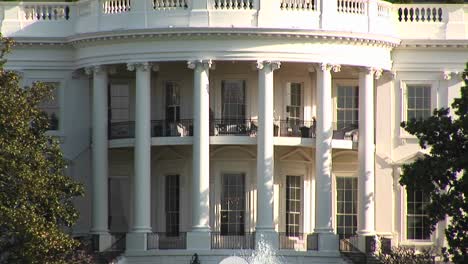 the camera pans up to show several people walking on the second floor balcony of the white house