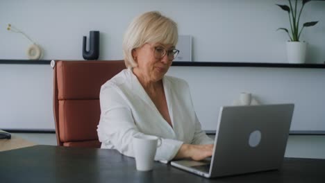 senior woman working on laptop in modern office