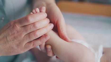 pediatra sostiene la pierna del bebé recién nacido y practica masaje