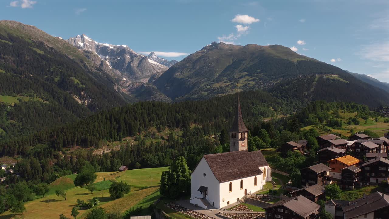 A charming alpine village with a church surrounded by lush green fields and mountains