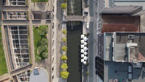 Aveiro-city-water-canal-with-canoe-and-buildings-rooftops,-top-down-aerial-drone-view