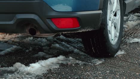 close up of a rear tire belonging to a subaru suv that backs up over a rocky and snowy road