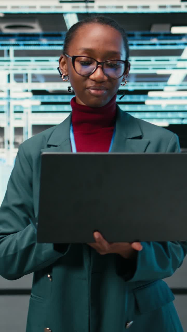 Vertical video Female technician walking in data center, using laptop and augmented reality