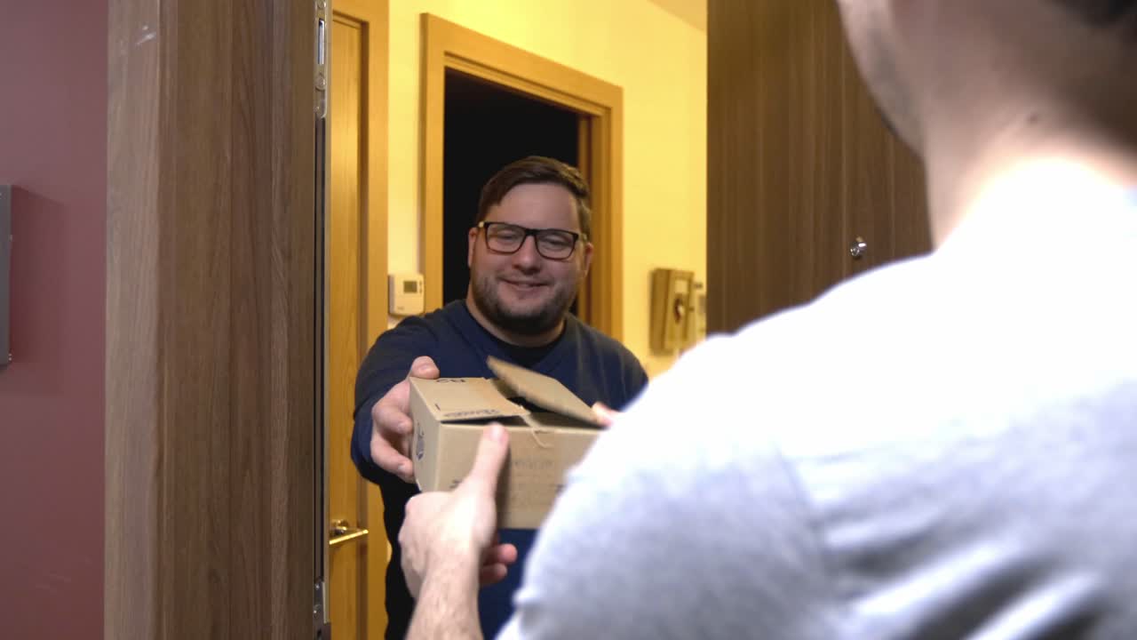 Male opening door receiving home delivery cardboard box online purchase parcel