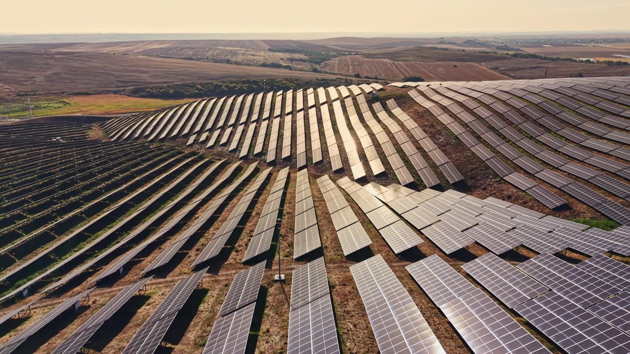 Solpaneler dækker et stort område på en vedvarende energifarm i et landligt landskab om dagen