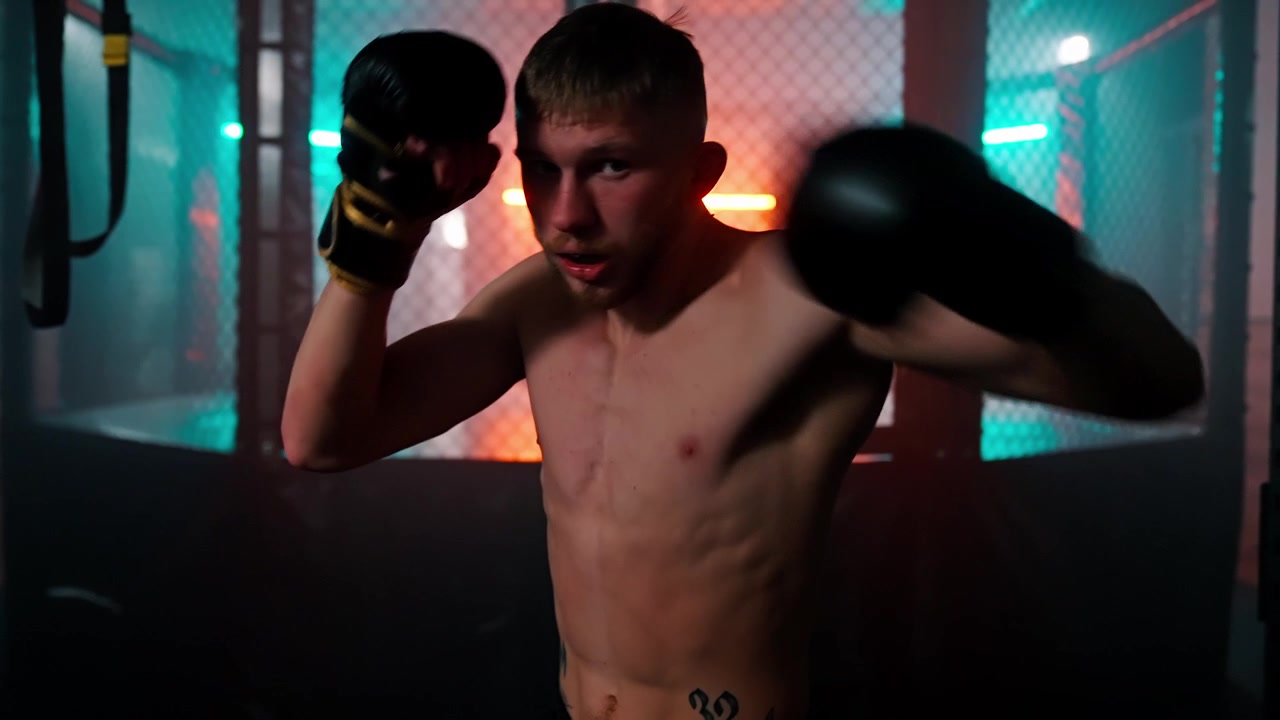 Pugile che fa shadow boxing in una palestra buia con luci al neon
