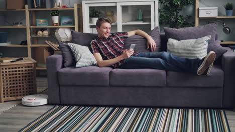 man relaxing on a sofa using smartphone