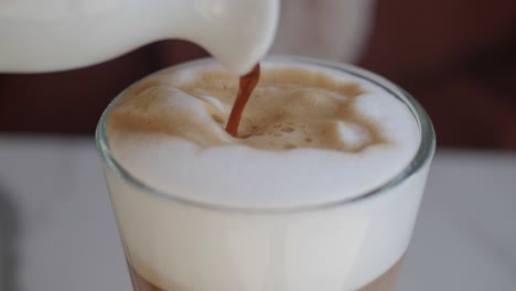 close-up of a latte being poured into a glass