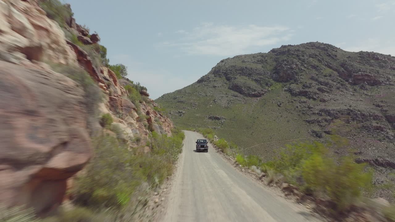 남아프리카 공화국의 세더버그 야생 지역에서 뒤로 날아가는 드론 - 도로에서 운전하는 오프 로드 차량의 전망 - 풍경은 매우 바위