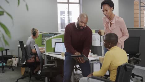 African-american-business-colleagues-discussing-work-in-office,-one-woman-in-wheelchair,-slow-motion