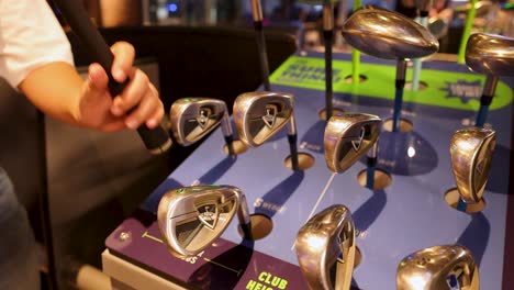 persona seleccionando un club de golf de la exhibición
