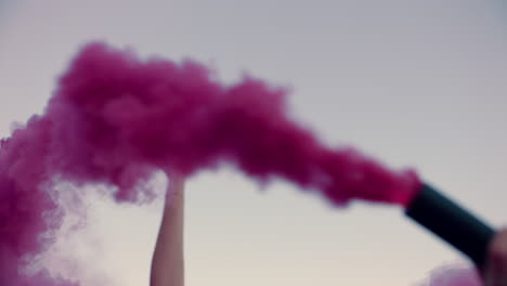 hermosa mujer agitando granada de humo rosa bailando en la playa temprano en la mañana celebrando la libertad creativa