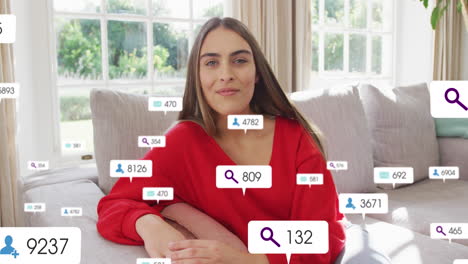 Animation-Von-Social-Media-Symbolen-Und-Zahlen-über-Einer-Kaukasischen-Frau-Zu-Hause