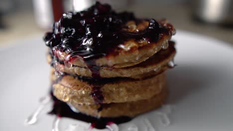 glazing four stacked pancakes and blueberry sauce with transparent syrup, slow motion
