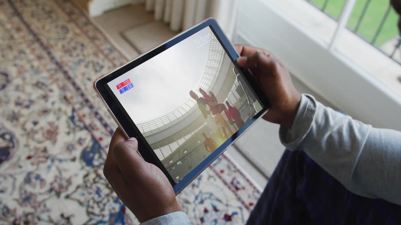 compuesto de un hombre sentado en casa viendo un partido de rugby en una tableta