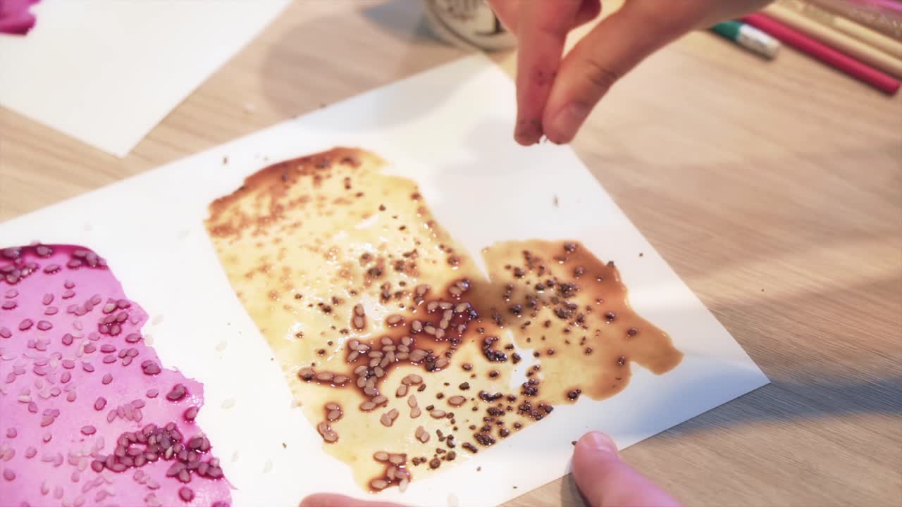 A woman in a studio painting on paper with red wine, coffee and rice, close view, slow motion