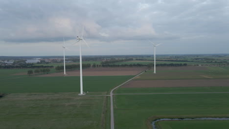 aerial jib up of three spinning windmills in rural area