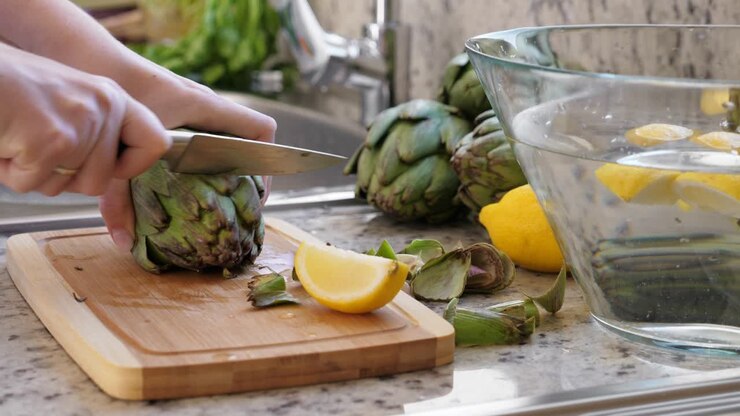 mujer cortar alcachofas. proceso de cocción en la cocina