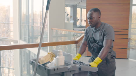 close up view of cleaning man carrying cleaning cart inside an office building