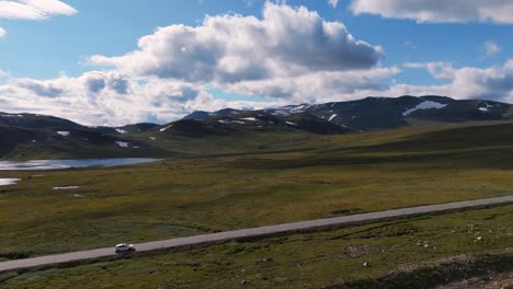 aerial shot of a car driving along a scenic mountain road in norway