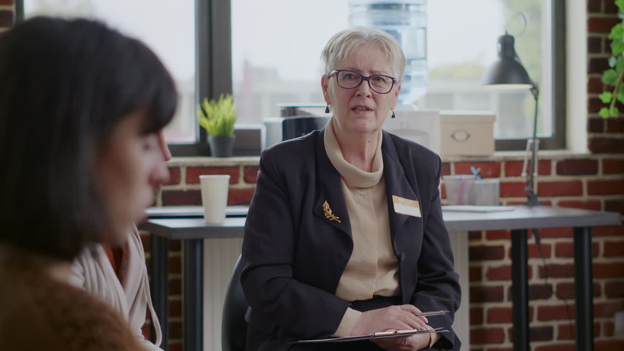 Close up of woman counselor having conversation with people in circle at aa therapy session