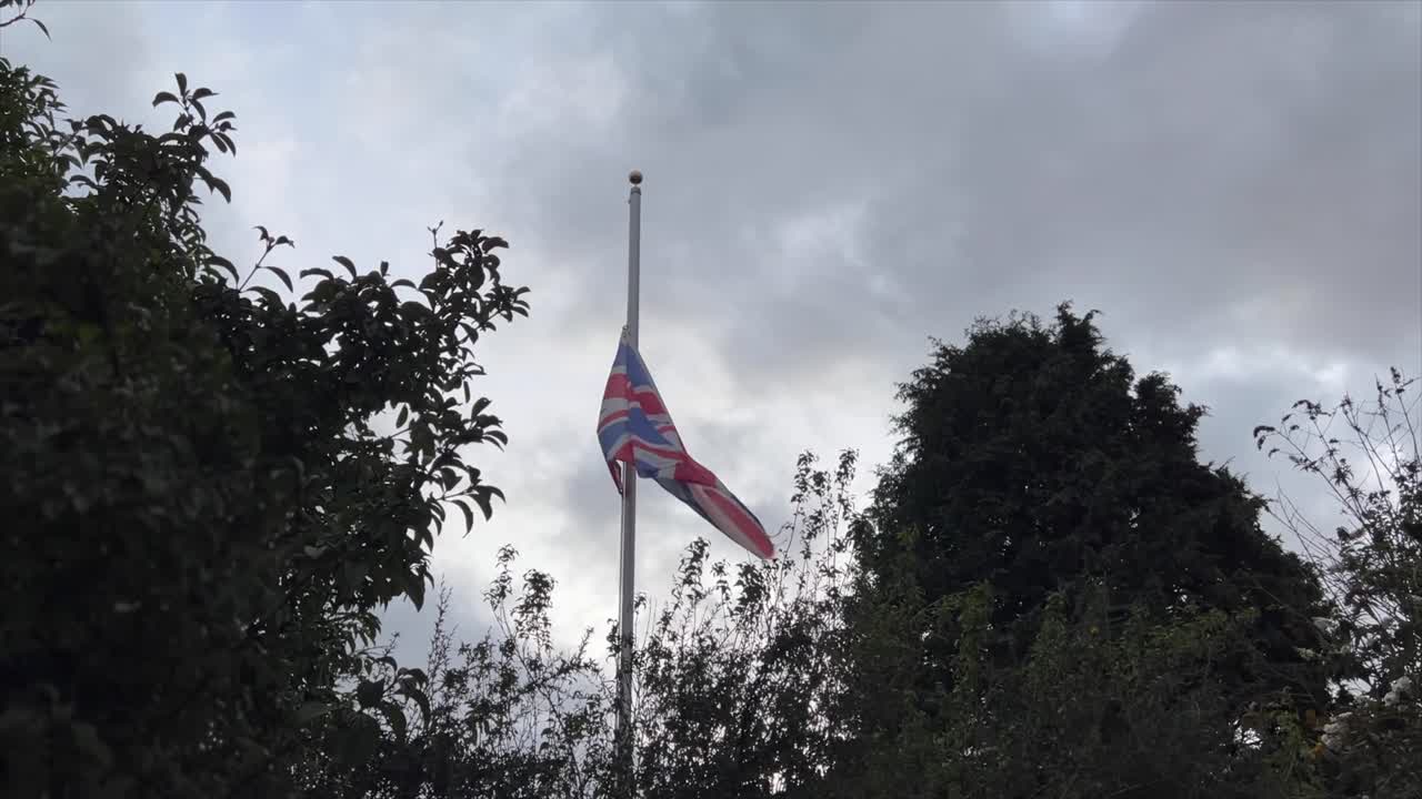 Bandiera Union Jack della Gran Bretagna sventola a mezz'asta tra gli alberi