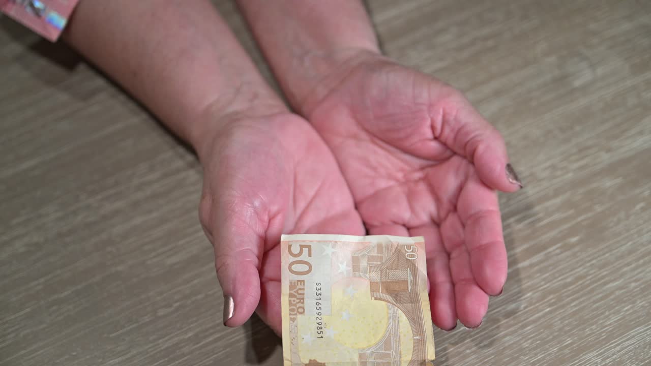 mujer anciana con las manos extendidas para atrapar la moneda europea restante