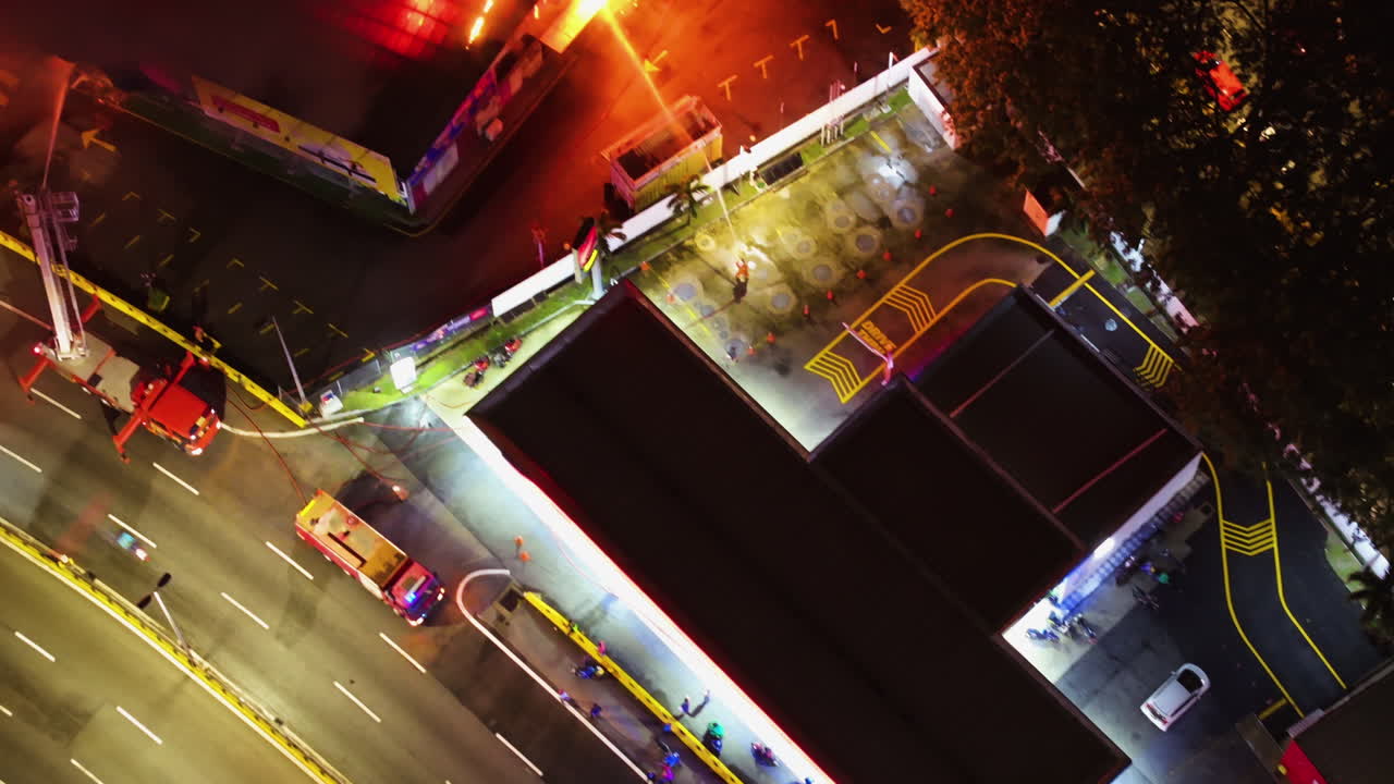 Aerial view above firefighters extinguishing a warehouse fire, night in Malaysia