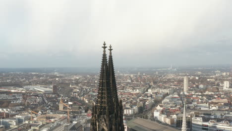 Top-of-tall-and-decorated-gothic-style-towers-of-Cathedral-Church-of-Saint-Peter.-City-panorama-in-background.-Cologne,-Germany