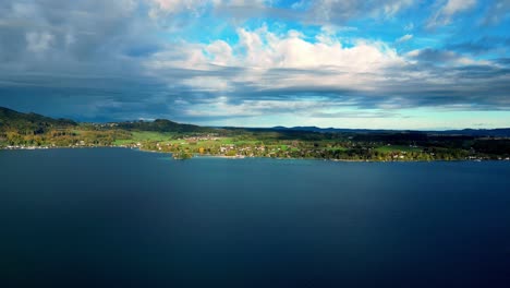 Lago-Cristalino-Rodeado-De-Majestuosas-Montañas-Cubiertas-De-Nieve-Bajo-Un-Cielo-Azul-Vibrante,-Capturado-En-Una-Toma-Amplia-Que-Muestra-La-Tranquilidad-De-La-Naturaleza