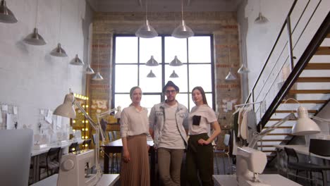 Acercar-El-Equipo-De-Diseñadores-De-Moda-Posando-Para-La-Cámara-En-El-Taller-De-Costura