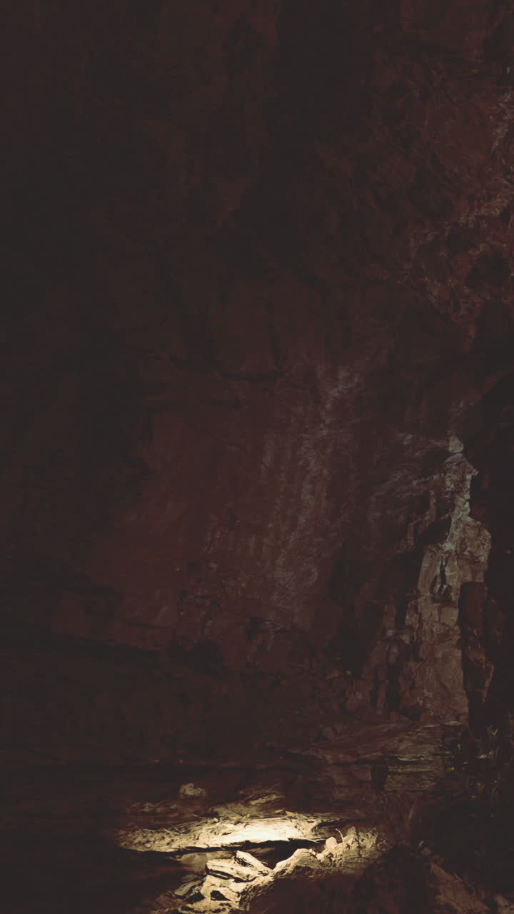 La luce illumina una superficie rocciosa all'interno di una grotta buia in una località remota.