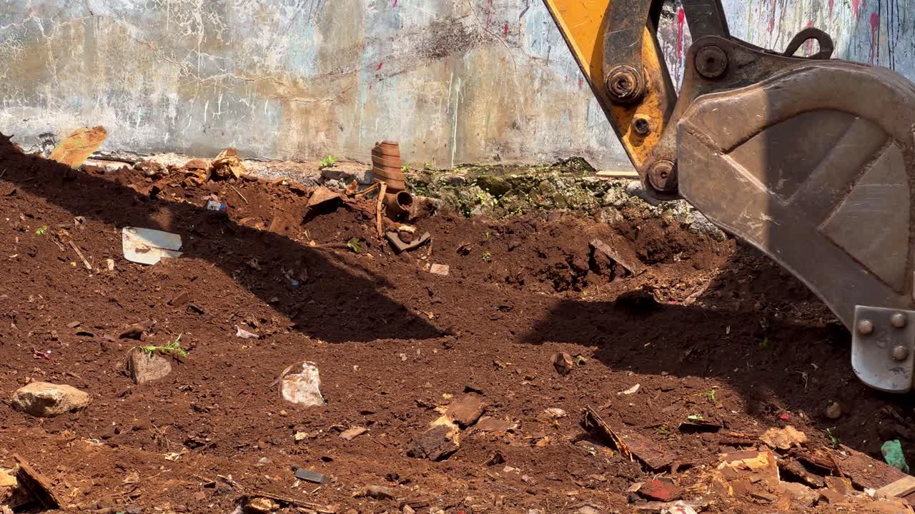 Heavy machinery excavator scoop breaking ground and moving dirt at a construction site