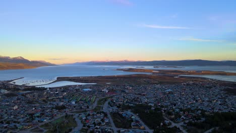 drone disparado volando sobre ushuaia al atardecer hacia el canal beagle