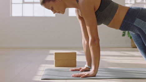 healthy yoga woman practicing downward-facing dog pose enjoying fitness lifestyle exercising in studio stretching beautiful body training on exercise mat at sunrise