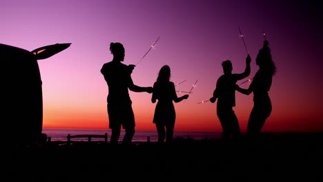 young adult friends having fun on the beach at night with sparklers 4k