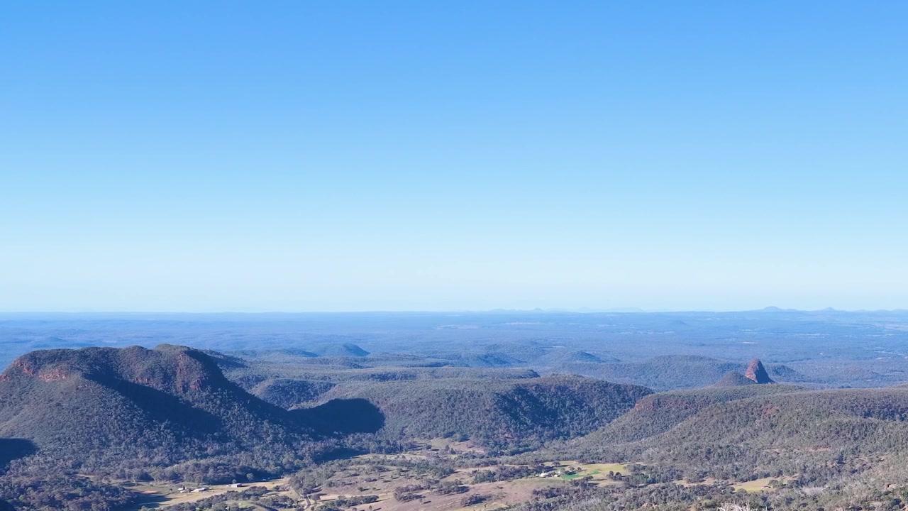 Wide panoramic shot of volcanic mountain ranges under clear blue skies in Warrumbungle National Park.