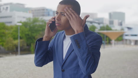 tired businessman rubbing forehead while talking on phone