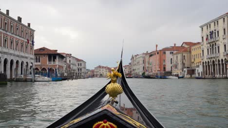 a black gondola adorned with gold decorations drifting through the canals of venice, italy - wide shot