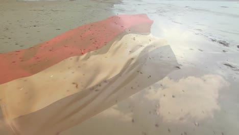 Digital-composition-of-waving-netherlands-flag-against-aerial-view-of-the-beach-and-sea-waves