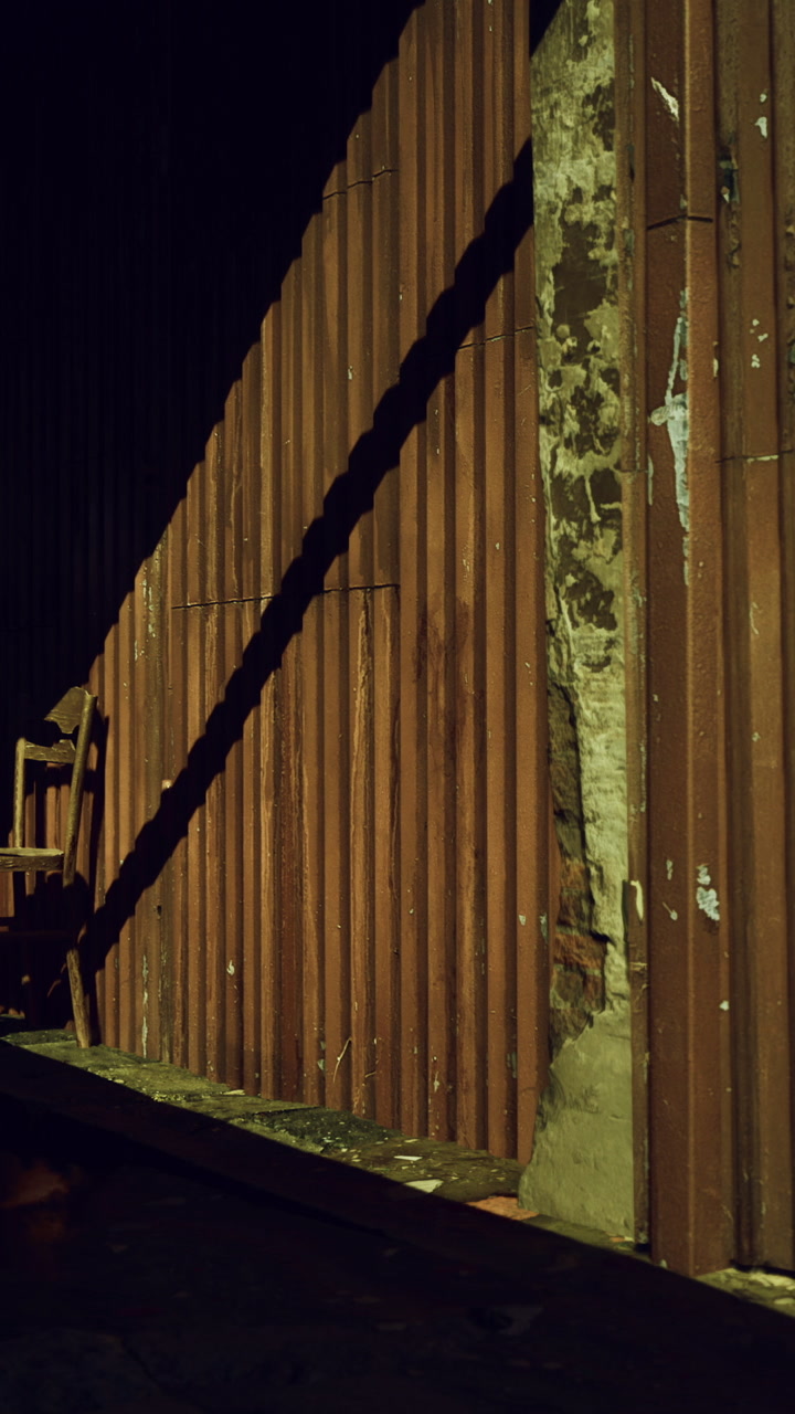 Light and shadow meet on a rusty wall during evening hours