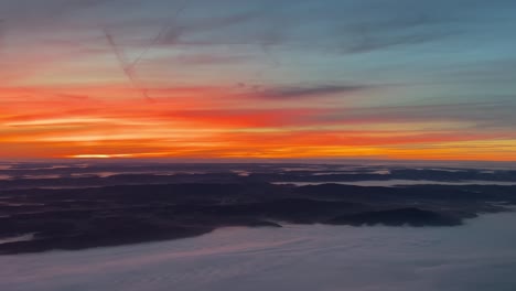 unique aerial view from a jet cockpit flying over germany at dawn with a colorful orange sky