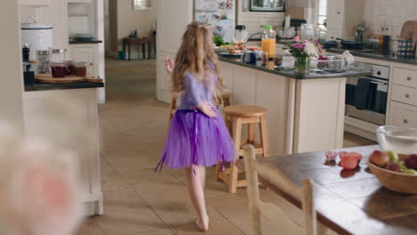 happy ballerina girl dancing in kitchen having fun practicing ballet dance moves wearing purple tutu at home