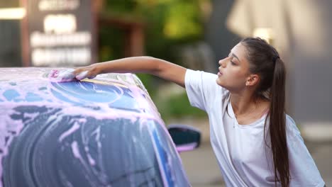 mujer lavando un coche con jabón rosa