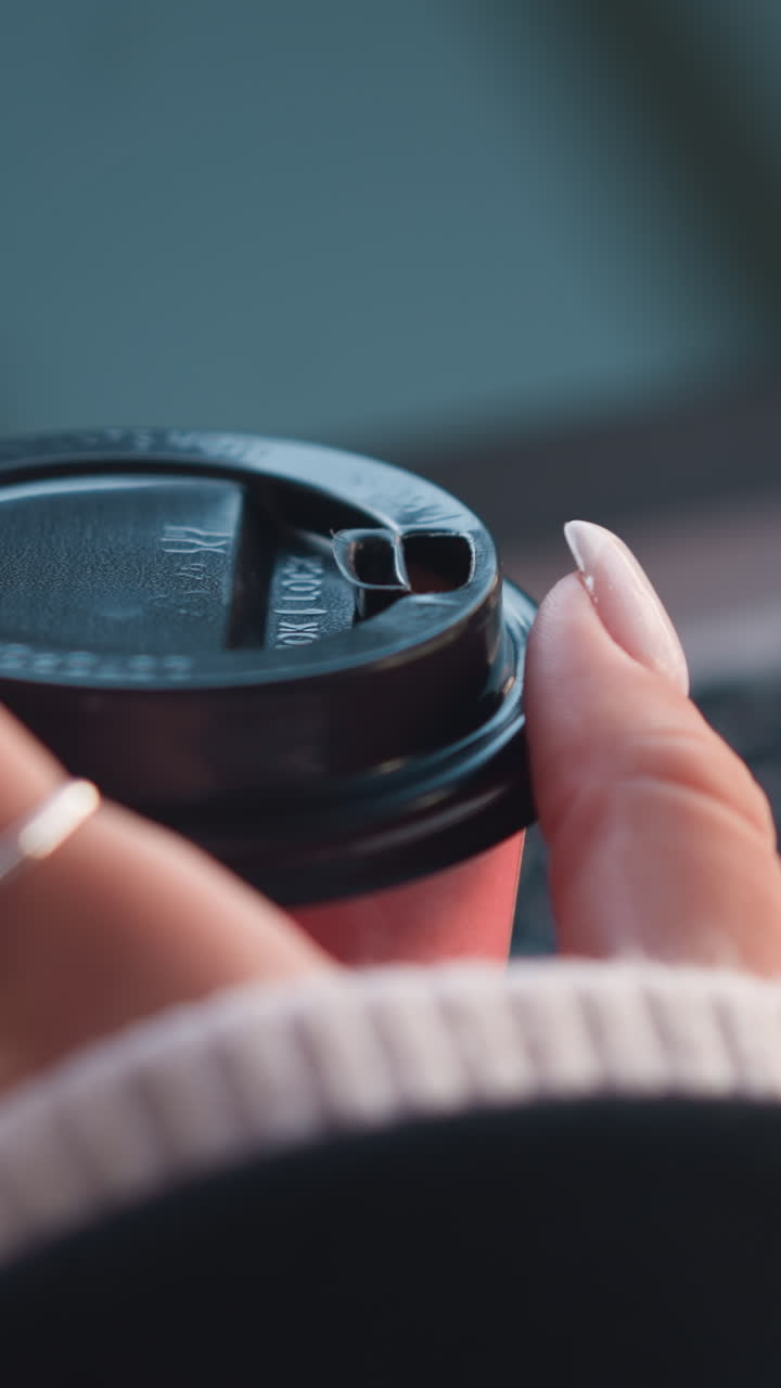 primer plano de la mano de la mujer girando suavemente la taza de café con los dedos cuidados, la computadora portátil borrosa en el fondo creando un ambiente de trabajo sofisticado