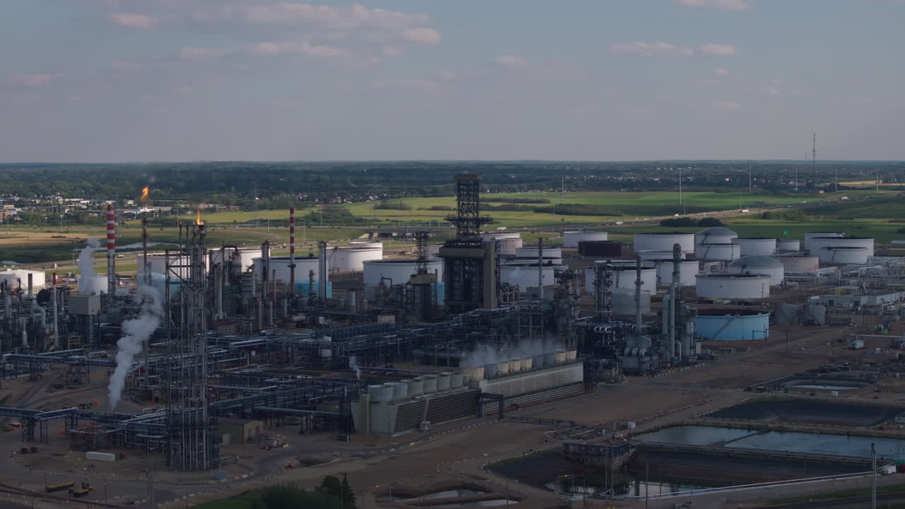 Industrial refinery complex with storage tanks and smokestacks at dusk